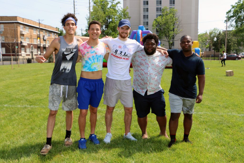 Five students outside at Trager Park, smiling on a sunny day