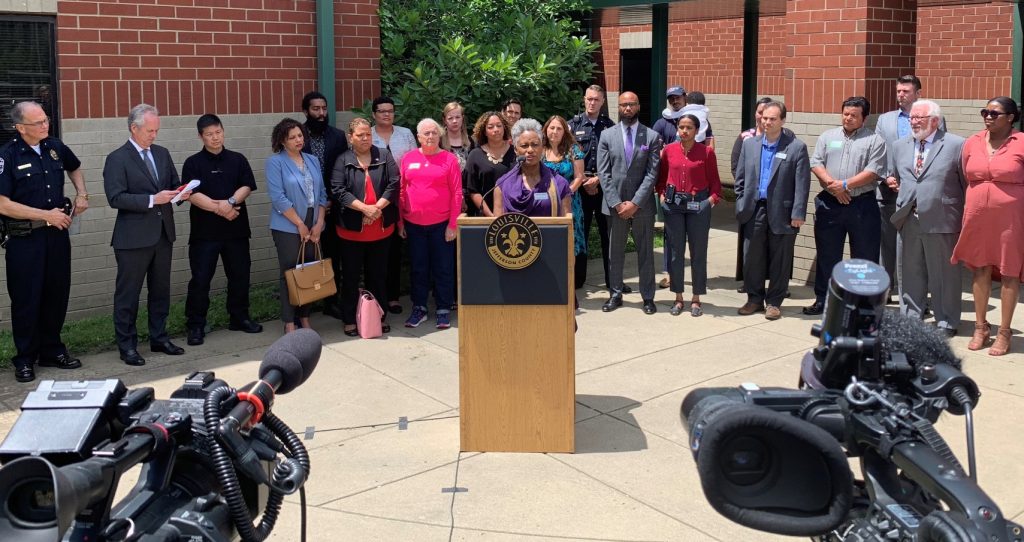 Chandra irvin, speaking at press conference, surrounded by about 20 people